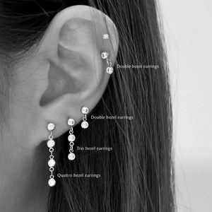 Detail of S925 silver bezel-set double and trio cubic zirconia earrings on model