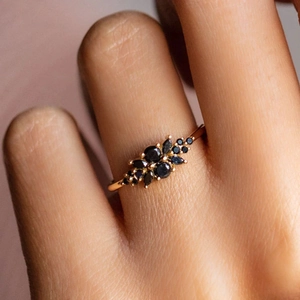 Close-up of gold band ring with black marquise cut stones in vintage cluster setting