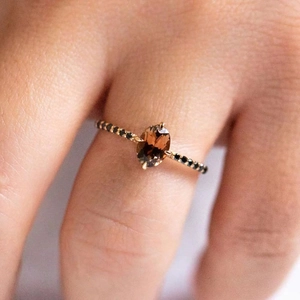 Detail of elegant S925 silver engagement ring with oval brown gemstone and black accents