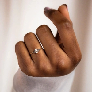Close-up of a marquise-cut white gemstone ring with black accent stones on a gold band