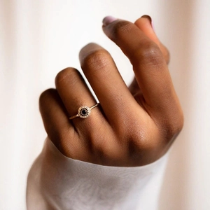 Macro shot of gold twist band ring featuring a round black gemstone and halo diamonds