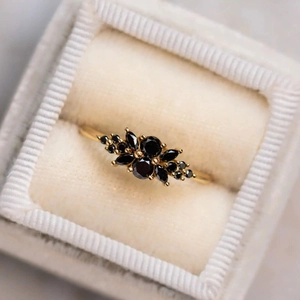 Macro detail of asymmetric black gemstones set in golden band on grey velvet box