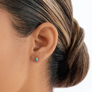 Detalle de pendiente triangular de turquesa con base dorada puesto en la oreja
