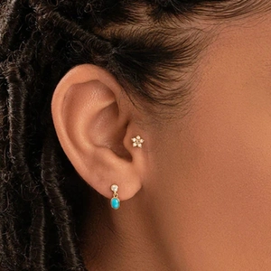 Detalle de pendientes vintage de oro con piedras azules y flores brillantes en una modelo