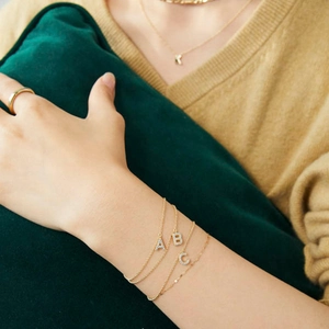 Detailed view of gold S925 sterling silver bracelets with cubic zirconia letter pendants