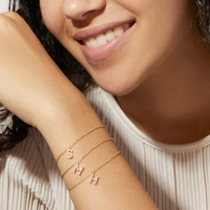 Detailed view of layered gold S925 silver bracelets with zircon S, M, H letter charms
