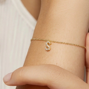 Close-up of S925 silver gold bracelet with sparkling zircon pavé initial S charm
