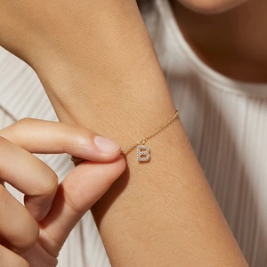 Close-up of S925 silver bracelet with gold finish and letter B pendant in cubic zirconia