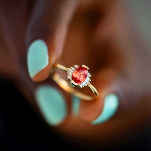 Macro shot of oval red gemstone ring with side baguette diamonds on golden band