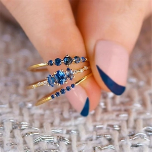 Macro shot of gold-plated stacked rings with deep blue gemstones and white crystals
