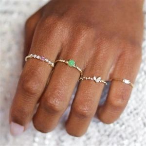 Close-up of stacked S925 silver gold-plated rings with pink, green and zircon stones