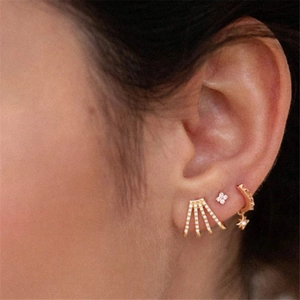 Detalle de pendientes tipo cuff de plata S925 dorada con dijes de estrellas y circonitas