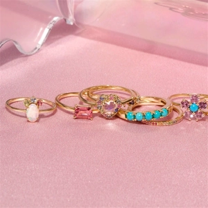 Detail of five assorted gold rings featuring colorful opal, pink stones, and heart gems