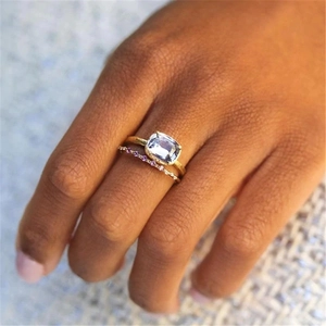 Close-up of double layered gold rings with square blue gemstone and purple accents