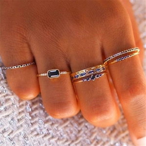 Macro view of stacked gold-finish rings featuring blue and purple gemstones on hand