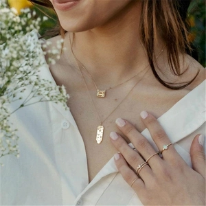 Close-up of layered gold necklaces with gemstone and engraved metal pendant for women