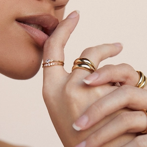 Detail of stacked gold S925 silver rings with zircon inlay on a model's hand