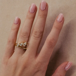 Close-up of golden double-layer ring with three pear-cut diamonds on a model hand