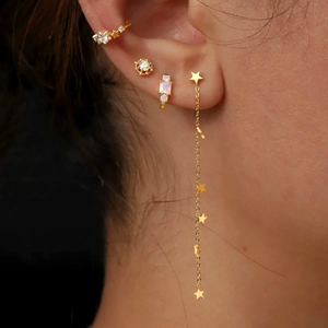 Macro detail of gold tassel star earrings and sparkling stud earrings for daily wear