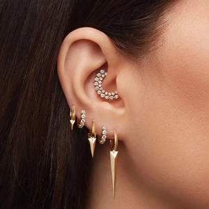 Primer plano de colgantes dorados de punta y aros con circonitas en una modelo mujer