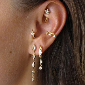 Macro shot of gold S925 silver earring set with zircons styled on multiple ear positions