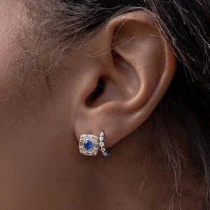 Close-up of stacked S925 silver hoop earrings and vintage blue sapphire stud set