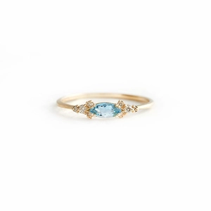 Macro shot of marquise-cut light blue sapphire set in a gold luxury engagement ring