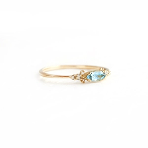 Macro shot of marquise-cut light blue gemstone ring with micro-diamond accents
