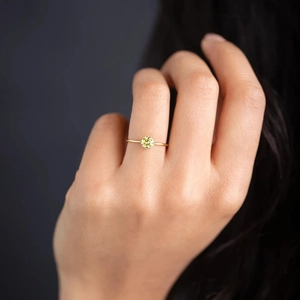 Nahaufnahme eines goldnen Rings mit rundem gelben Edelstein in minimalistischem Design