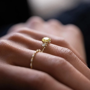 Makroaufnahme von gelbem Edelsteinring mit Pavé-Diamanten und feinen Perlenrand-Details