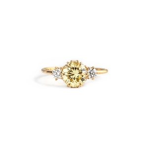Detail eines Dreisteinrings mit gelbem Mittelstein und klaren Seitendiamanten auf Gold