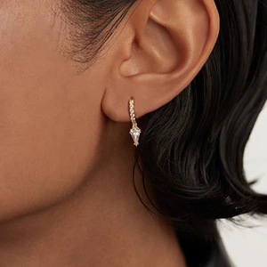 Primer plano de pendientes de aro dorados con cristal de talla marquesa en una modelo