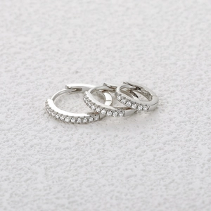 Macro detail of three S925 sterling silver hoop earrings with clear pave moissanite stones