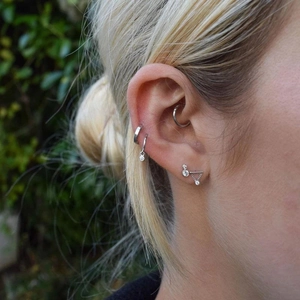 Macro shot of s925 silver fringe chain earrings with diamonds on a female ear