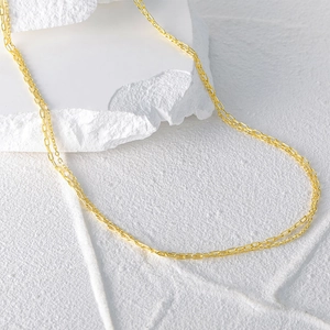 Detailansicht der goldenen Gliederkette auf einer weißen Steinstruktur