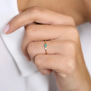 Detailansicht eines schmalen Goldrings mit grünem Smaragd und kleinem Diamantbesatz