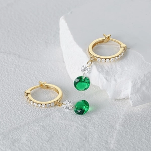 Vista macro detallada de los aros dorados con colgantes de circonita verde esmeralda y clara