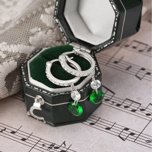 Detalle macro de pendientes de esmeralda con circonitas en estuche de terciopelo verde