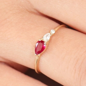 Makroaufnahme eines minimalistischen Goldrings mit Rubin im Birnenschliff und Diamant