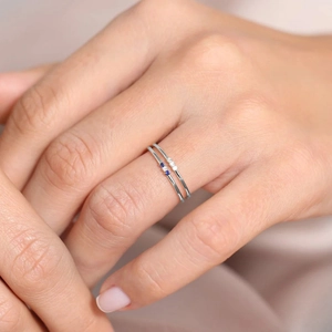 Macro detail of 925 silver rings with three tiny blue and white stones on hand
