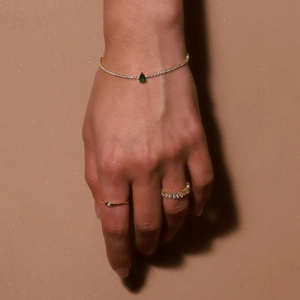 Close-up of S925 silver gold bracelet with pear-cut emerald green gemstone and cubic zirconia