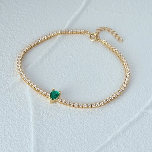 Detail of S925 silver tennis bracelet with green pear-cut stone and gold plating