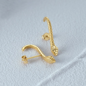 Macro detail of gold snake stud earrings showing textured scales and 925 silver hallmarks