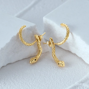 Detailed view of gold snake stud earrings with engraved scales and black zircon eyes