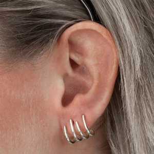 Detalle de pendiente de oreja minimalista de plata de ley S925 puesto en la oreja