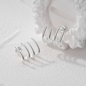 Detalle de pendientes de garra en plata de ley S925 con textura metálica y sello distintivo