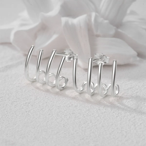 Vista macro de pendientes minimalistas de plata de ley S925 con diseño de cuatro garras pulidas