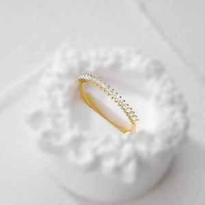 Macro di un anello minimalista in argento S925 dorato con una fila di zirconi brillanti