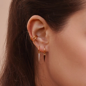 Close-up of gold ear cuff set with spike pendants and cubic zirconia on a model