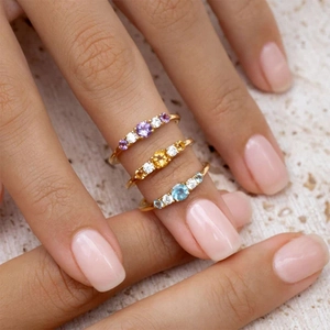 Detail view of gold stacked rings featuring amethyst, citrine and blue topaz stones